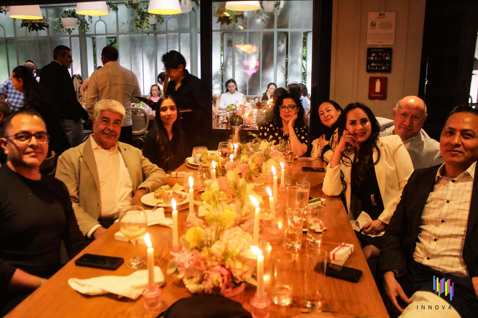 Invitados en una mesa con flores y velas durante un evento